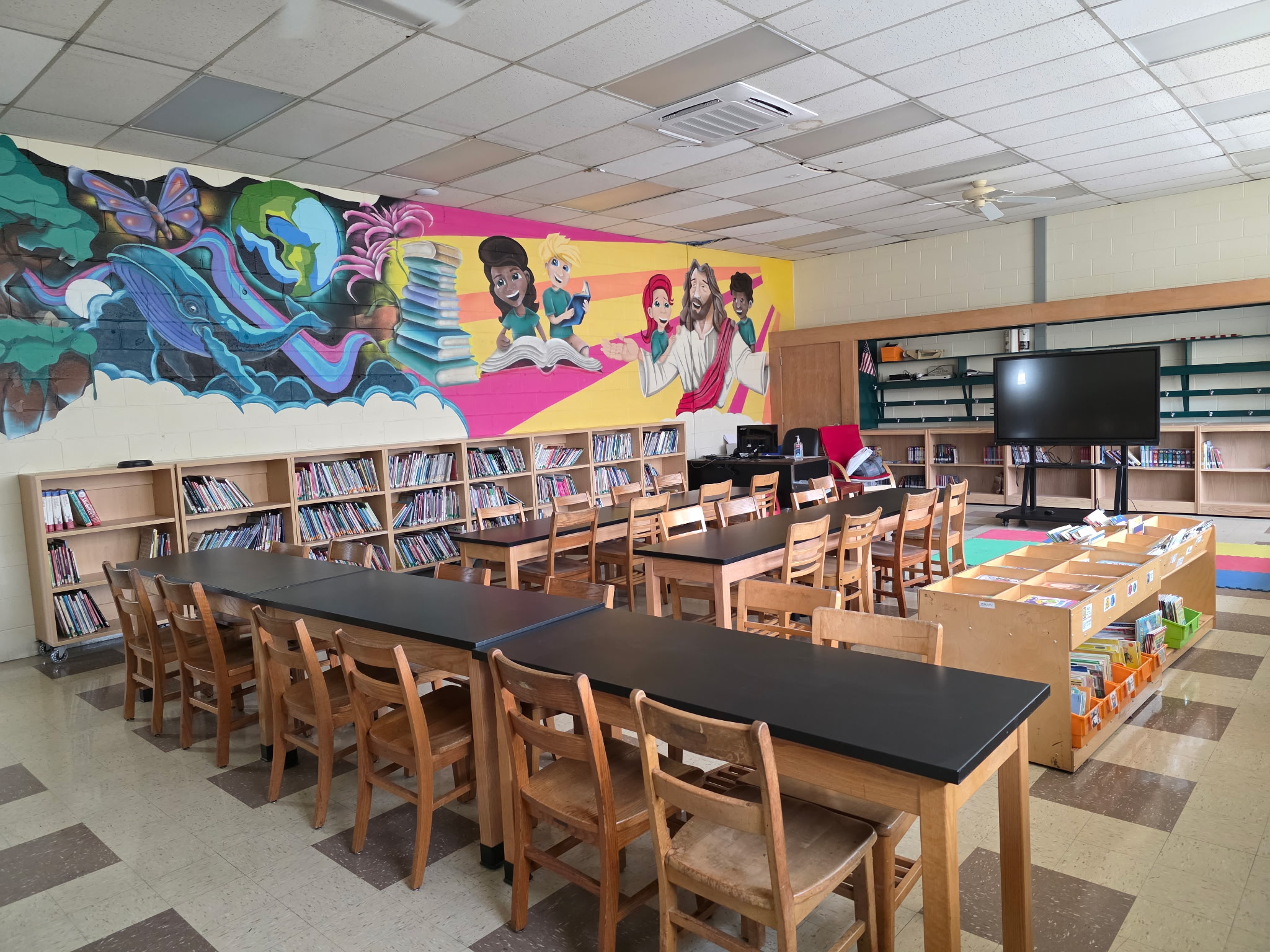 Holy Cross School Library - wide view showing mural, tables, and bookshelves